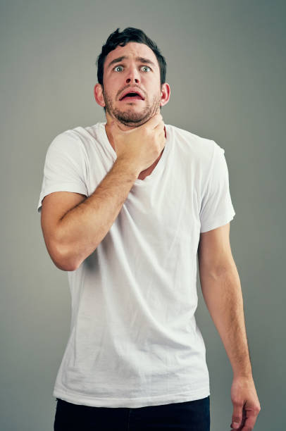 When you stressed out and can't take the pressure Studio shot of a casual young man posing against a grey background choking stock pictures, royalty-free photos & images