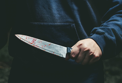 A man with a bloody knife in his hand close up.