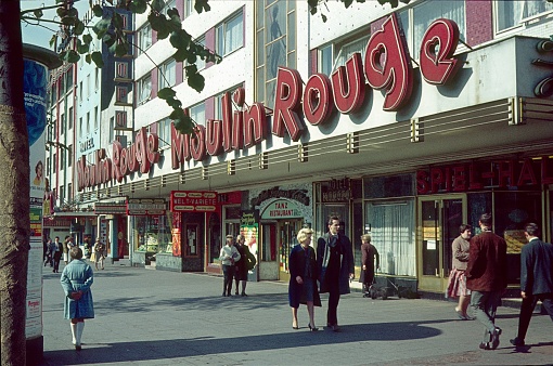 Reeperbahn, Hamburg, Germany, 1962. The busy entertainment quarter in St. Pauli / Hamburg. On display here is the former Moulin Rouge on the Reeperbahn in St. Pauli. It was an offshoot of the famous Varietétheater from Paris. In 2016, it finally closed the doors. Furthermore: strolling pedestrian.