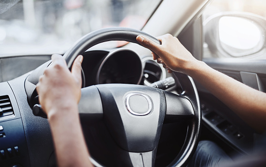 Cropped shot of a man’s hands at the 10 and 2 position on a steering wheel of a car