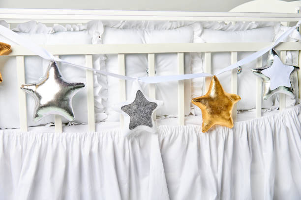 istock Silver, gold and white star shaped pillows on a white baby cot 883839526