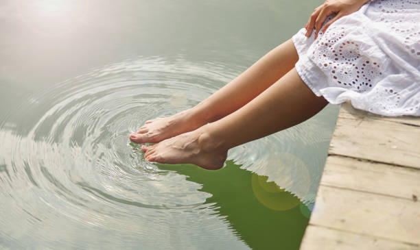 istock Women's feet in the water 883841282