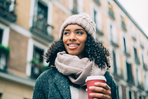 Young black woman drinking coffee wandering in the streets of Madrid on winter