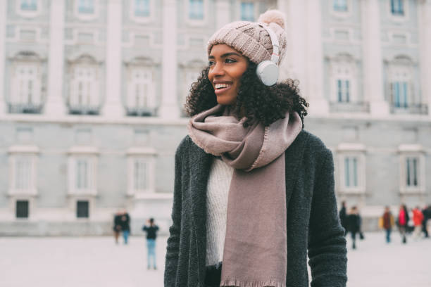 若い黒の女性音楽を聴くと冬"n の王宮近くの携帯電話の上で踊って - african descent women american culture human hair ストックフォトと画像