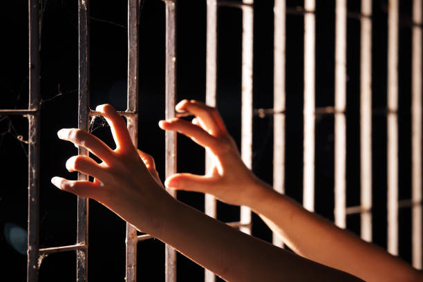 istock hands of prisoner in jail as background. 883885212