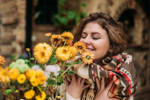 黄色の花の近くに立って、臭いがする女性の肖像画。 - nature curly hair smiling human face ストックフォトと画像