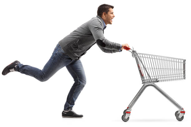 istock Guy running and pushing an empty shopping cart isolated on white background 883887588