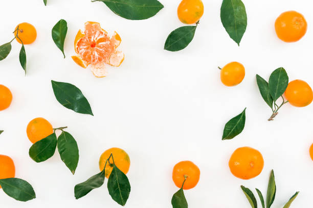 Frame of citrus - mandarin and leaves on white background. Flat lay. Top view