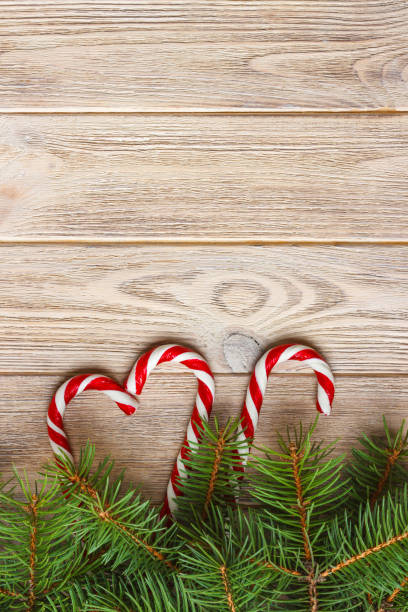 istock Christmas tree branch and candy cane on a wooden table or board for background. New year theme. Space for text 883953230