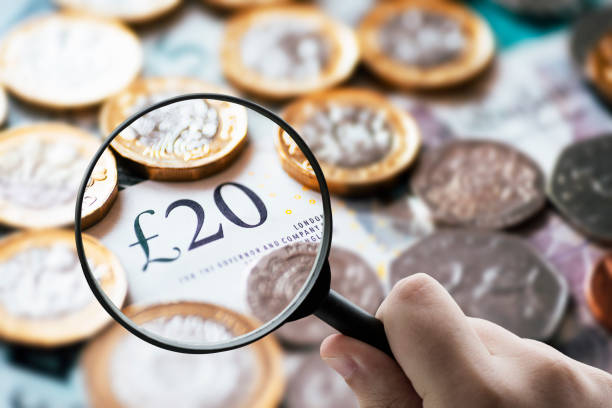 istock Focusing on money - Magnifying glass over British pound notes. 883960288