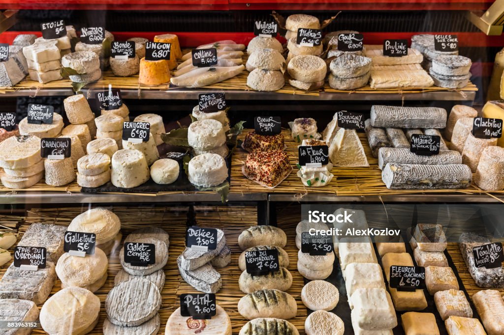 Different cheeses on the counter of a small store at the Aligre Market. Paris, France A large selection of different french and italian cheeses on the counter of a small store at the Aligre Market (Marche d'Aligre) in the Bastille district. Paris, France Cheese Stock Photo