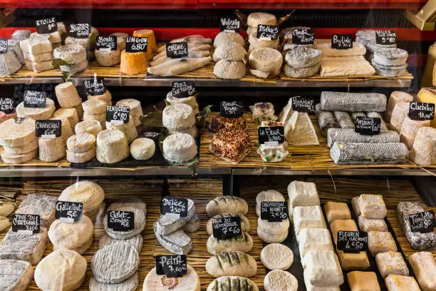 A large selection of different french and italian cheeses on the counter of a small store at the Aligre Market (Marche d'Aligre) in the Bastille district. Paris, France