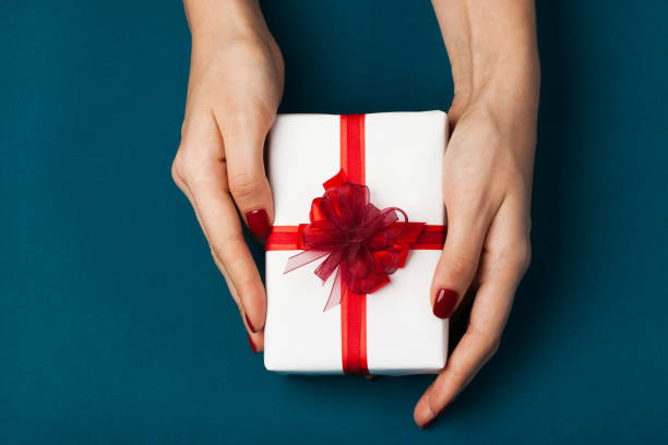 istock Beautiful female hands with a wrapped present 883969030