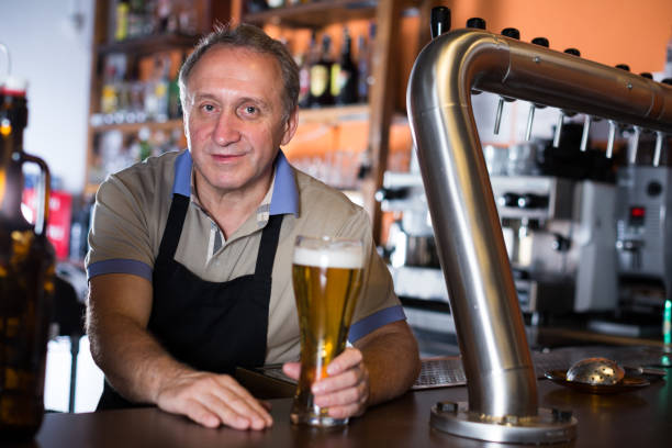 istock Smiling barman is offering unbottled beer to next client 883970364
