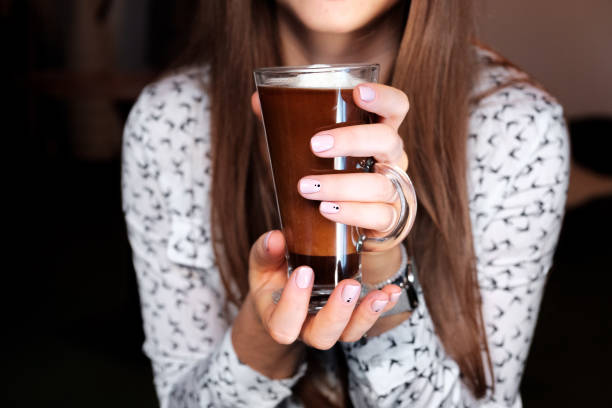 istock Cappuccino through the glass held by a woman 883973108