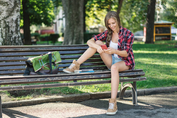 istock Blond woman texting on her mobile phone in the park 883977602