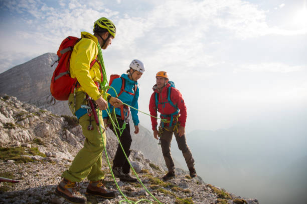 istock Climber helping teammate climb steep cliff 883977990