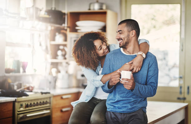 Don't forget how much I love you Shot of a happy young couple relaxing in the kitchen in the at home young couple stock pictures, royalty-free photos & images