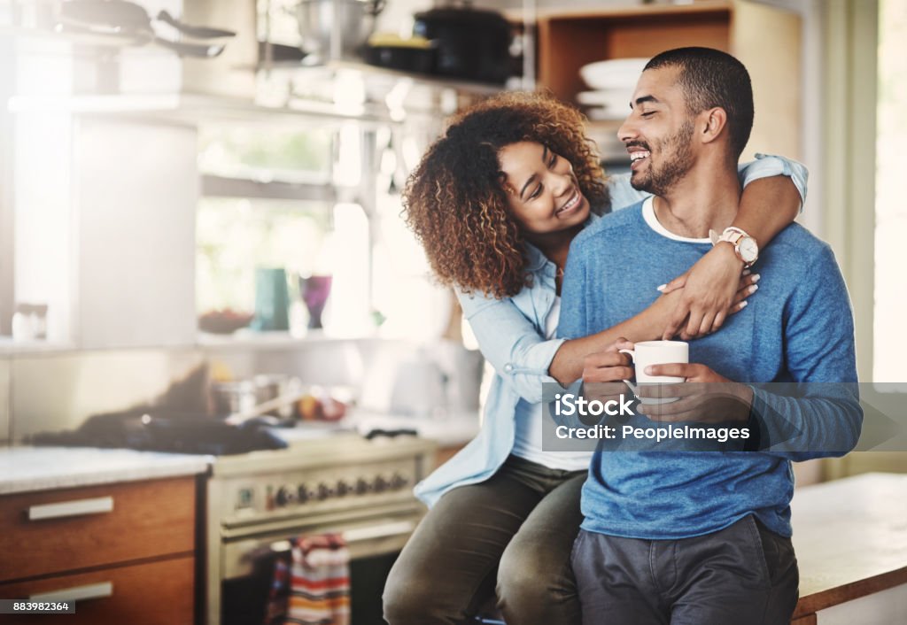 You make me a happy man Shot of a happy young couple relaxing in the kitchen in the at home Couple - Relationship Stock Photo