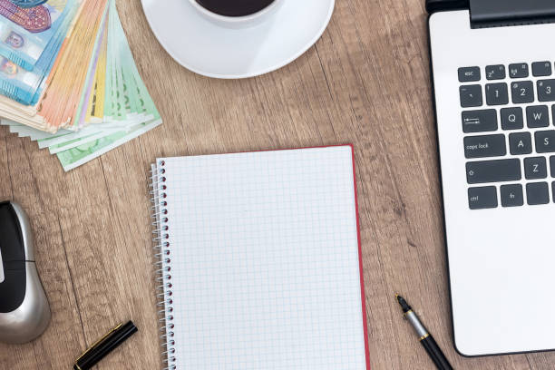 istock laptop, pen, euro banknote and notepad on desk. 883987480