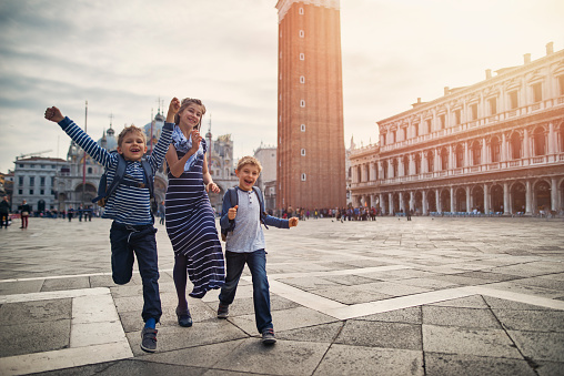 Excited kids visiting Venice, Italy. They are running happily in Piazza San Marco. 

