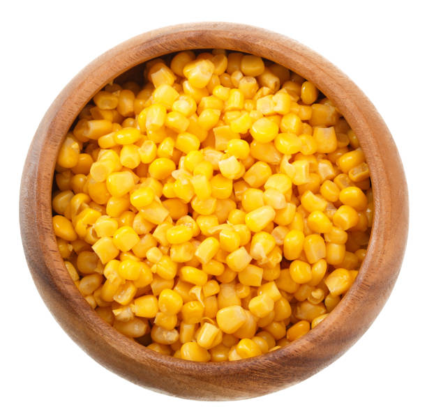 istock Corn seeds in a wooden bowl isolated on white background. Top view. 884003402