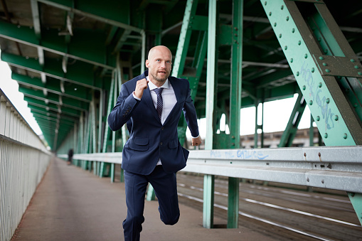 Businessman full of energy running and climbing on a bridge. Celebrating success. Being in a rush