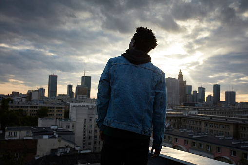 African ethnicity man lookin at view from a rooftop, Sunset