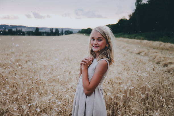 Beautiful cute girl in a wheat field in a beige dress in flying confetti.