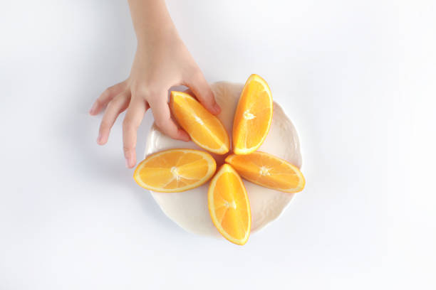 Close up kid's hand holding a slice of orange fruit, ready to eat.