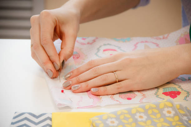istock Young seamstress measuring the length with pins 884019864