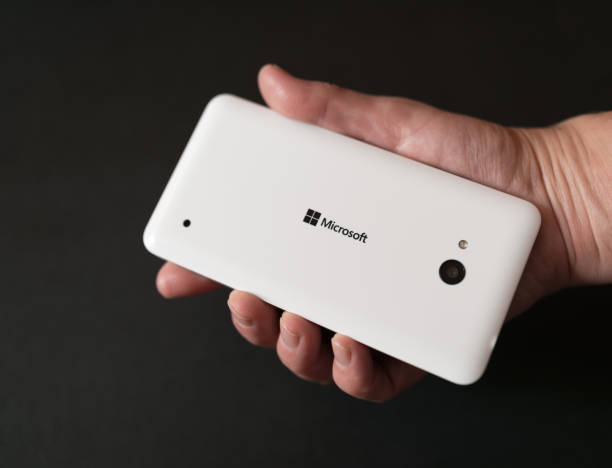 White Microsoft Lumia smartphone. VLADIVOSTOK, RUSSIA - SEPTEMBER 25, 2015: Microsoft Lumia smartphone in hand on black background. Microsoft Corporation is an American multinational technology company. phone nokia stock pictures, royalty-free photos & images