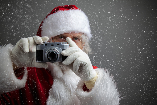 Santa Claus taking picture with old camera. dark background with snow