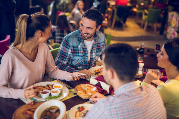 若い女性の友人と昼食時に携帯電話を使用して - gastro pub ストックフォトと画像