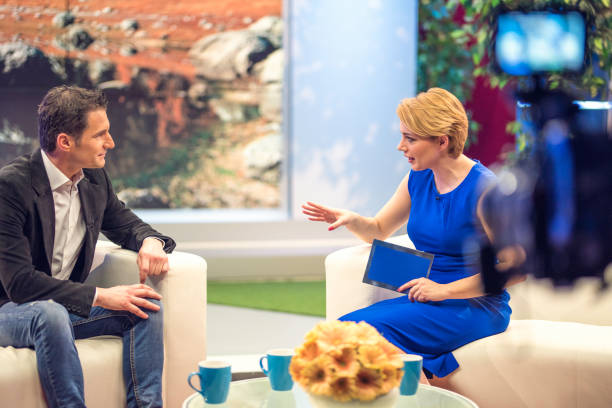 Filming a talk show Talk show host interviewing guest. Blurred camera in foreground. broadcast studio stock pictures, royalty-free photos & images