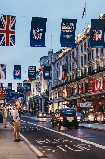 Black taxi and red bus on Regent Street, London. The street is decorated with NFL flags to celebrate the event and four NFL games played in capital in 2017.