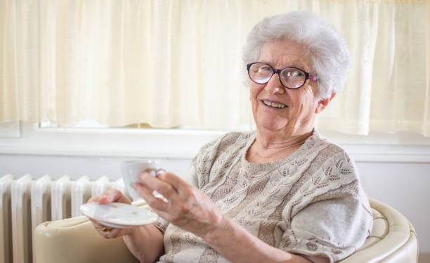 Smiling grandmother drinking coffee at home.