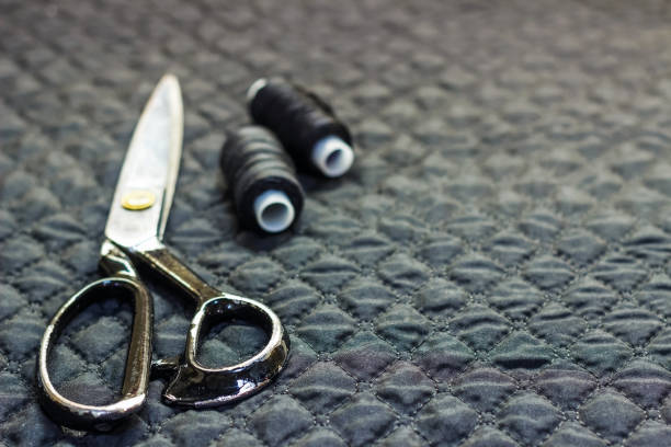 istock On a black quilted fabric, close-up, lie scissors and thread with a needle. 884076294