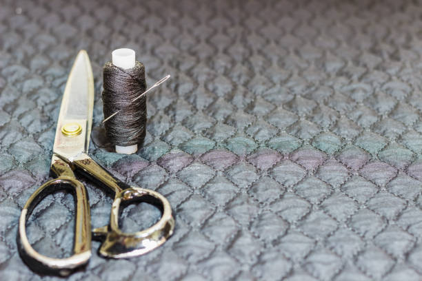 istock On a black quilted fabric, close-up, lie scissors and thread with a needle. 884076358