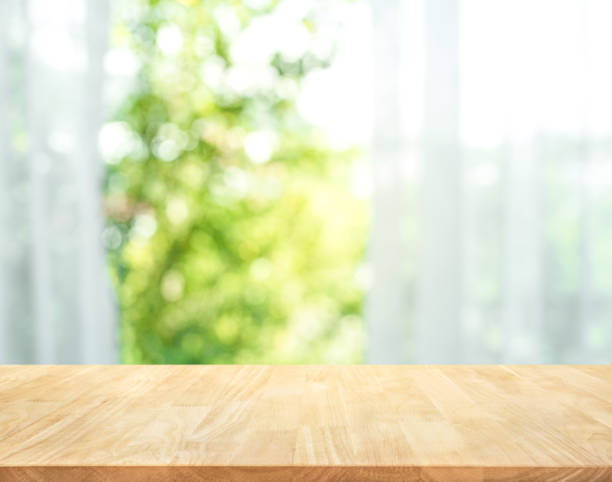 Wood table on blur of curtain with window view garden Empty of wood table top on blur of curtain with window view green from tree garden background.For montage product display or design key visual layout sunny window stock pictures, royalty-free photos & images