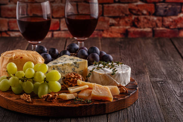 istock Cheese, nuts, grapes and red wine on wooden background 884083578