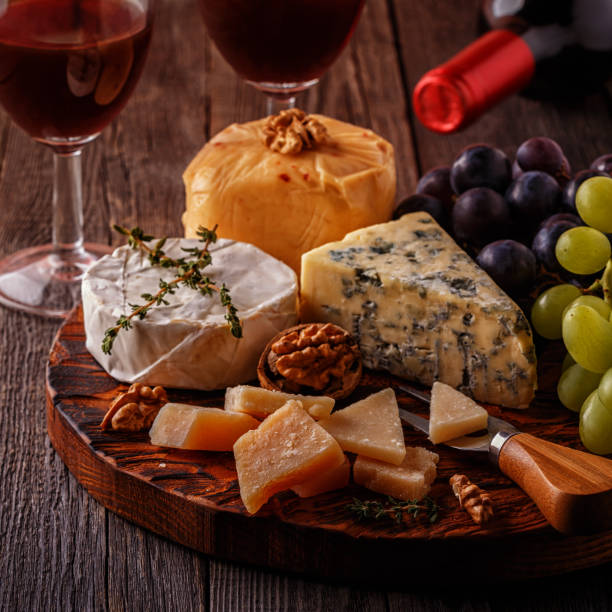 istock Cheese, nuts, grapes and red wine on wooden background 884083592