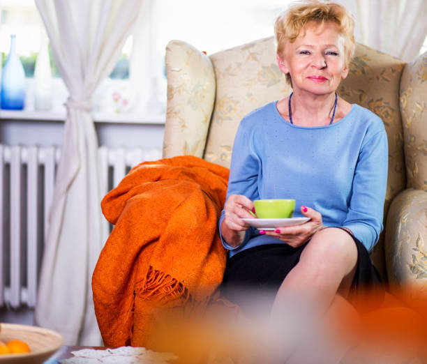 Elderly woman drinking tea at home.