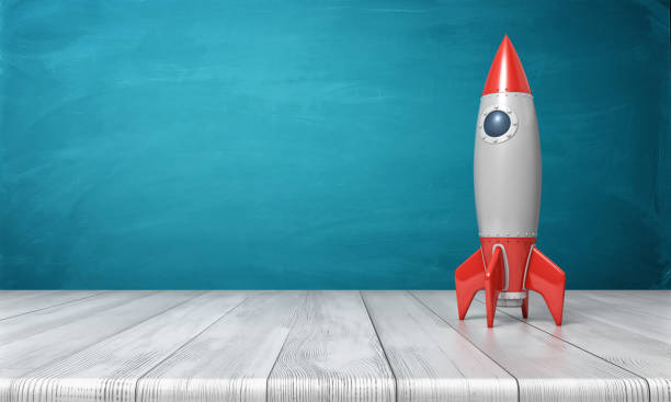 3d rendering of a red and silver realistic model of a retro rocket stands on a wooden desk on a blue background 3d rendering of a red and silver realistic model of a retro rocket stands on a wooden desk on a blue background. Science fair. Goals and dreams. Fly in space. model rocket stock pictures, royalty-free photos & images