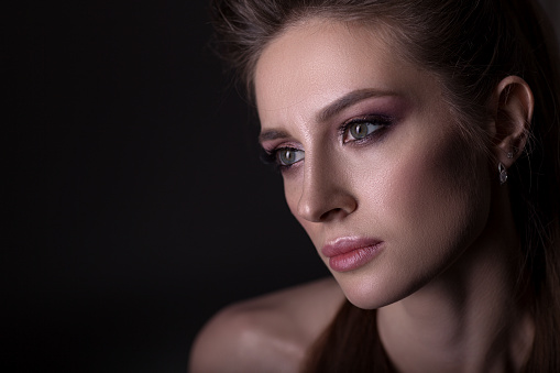 Portrait of a beautiful woman on a dark background, with a beautiful make-up and hairstyle