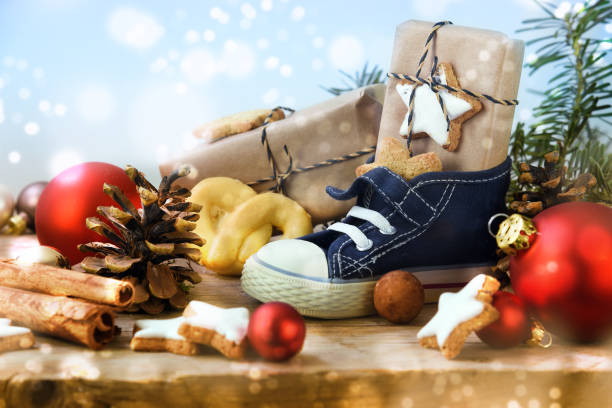 dzień świętego mikołaja, buty dziecięce ze słodyczami, prezenty i ozdoby świąteczne na rustykalnym drewnie, jasnoniebieskie śnieżne tło, w niemczech zwane nikolaus - gift blue christmas religious celebration zdjęcia i obrazy z banku zdjęć