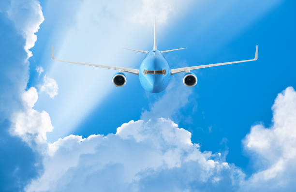 istock Airplane flying in the blue sky among clouds and sunlight 884127718