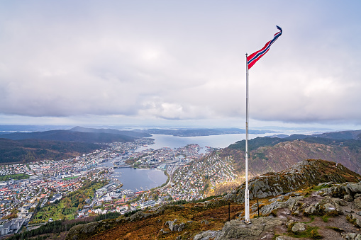 Norwegian flag fluttering on a wind on a pole on top of Mount Ulriken, Bergen, Norway
