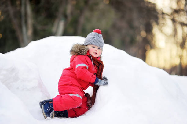 istock Little boy in red winter clothes having fun with fresh snow 884149078