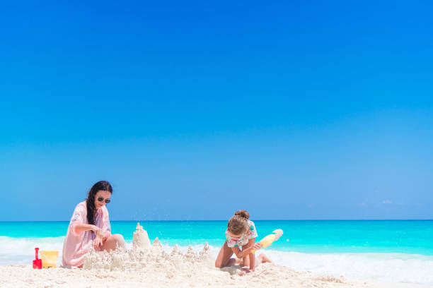 istock Mother and little kid making sand castle at tropical beach 884152170
